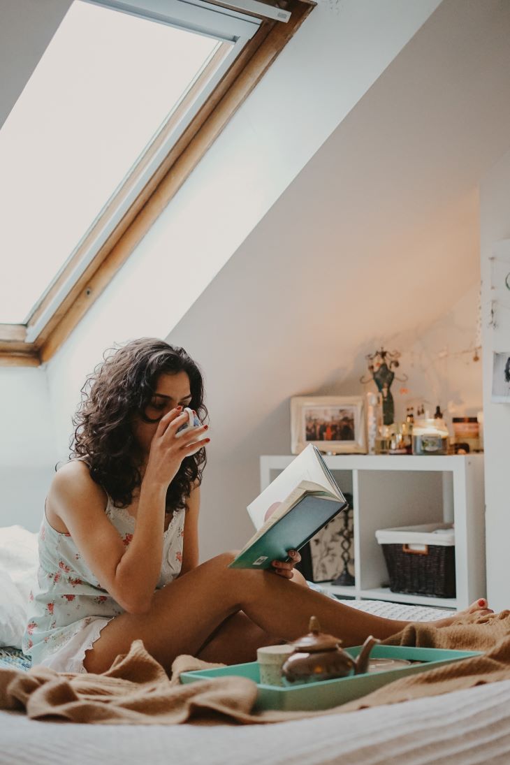 Girl On Bed Sipping Her Coffee and Reading a Book