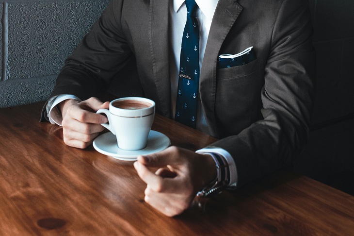 A Man in Suit Having Coffee
